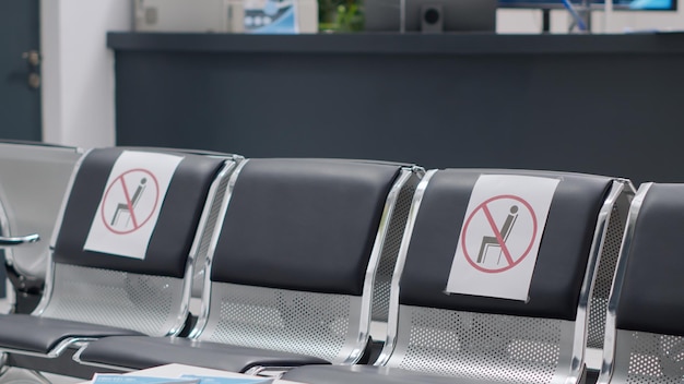 Photo nobody in hospital reception lobby with empty chairs during coronavirus pandemic, virus epidemic prevention. no people with medical appointment in waiting room at healthcare facility.