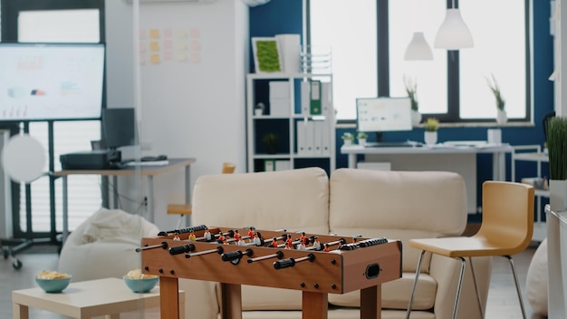 Nobody in workplace used for meeting with businesspeople after work. Empty office with foosball table to play football game, bottles of beer and snacks, enjoying party celebration