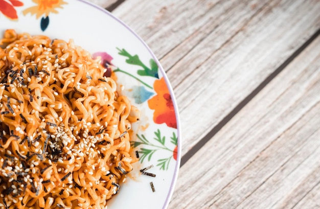 Foto noedels of pittige hakka noedels or chow mein in een witte plaat op houten achtergrond schezwan noedels is een warm gerecht van de indochinese keuken met udon noedels zeewier en chili saus