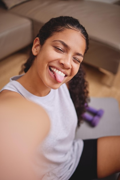 Foto nog een geweldige zweetsessie in de boeken shot van een aantrekkelijke jonge vrouw die zit en een selfie maakt na haar training in haar woonkamer