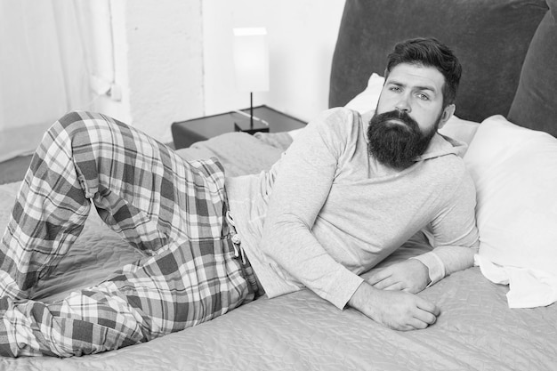 Nog een minuut in bed energie en vermoeidheid bebaarde man hipster wil slapen in de ochtend brute slaperige man in slaapkamer volwassen man met baard in pyjama op bed in slaap en wakker comfort bed