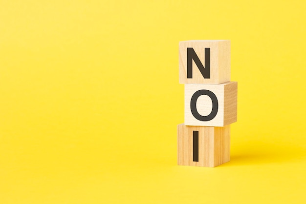 NOI text on wooden cubes on yellow background