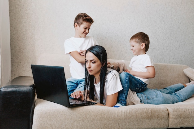 Шумные дети отвлекают мам от работы за компьютером, раздраженная мама держит ее за голову