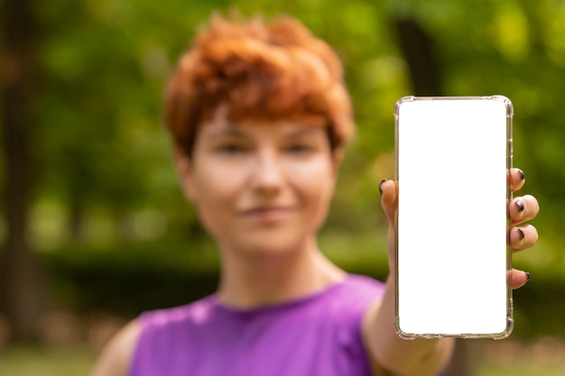 Non binary person showing smartphone in park