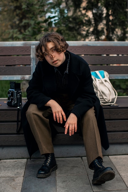 Non binary person sitting and posing on a bench