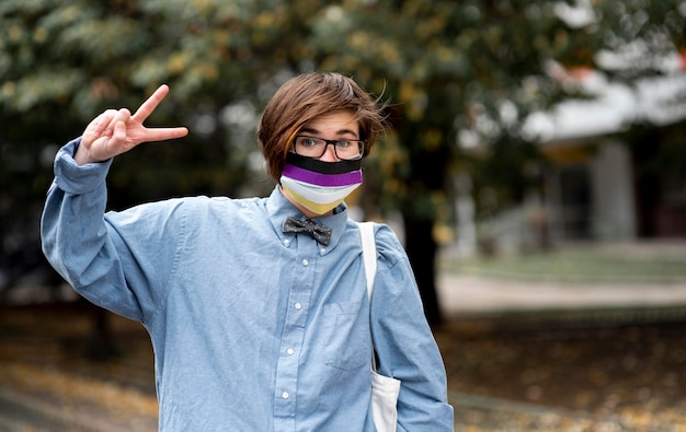 Photo non binary person with glasses doing the peace sign