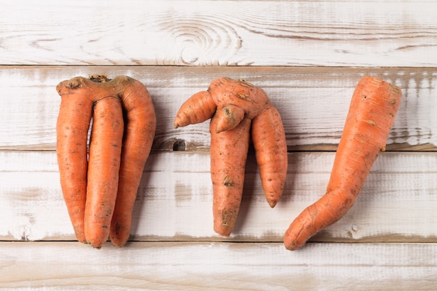 Non- standard ugly carrots on an old painted wooden background. Flat lay.