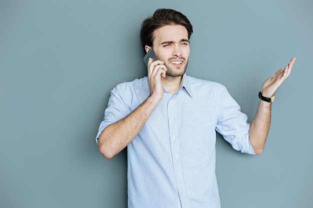 Comunicazione non verbale. bell'uomo piacevole piacevole parla al telefono e gesticola mentre esprime le sue emozioni