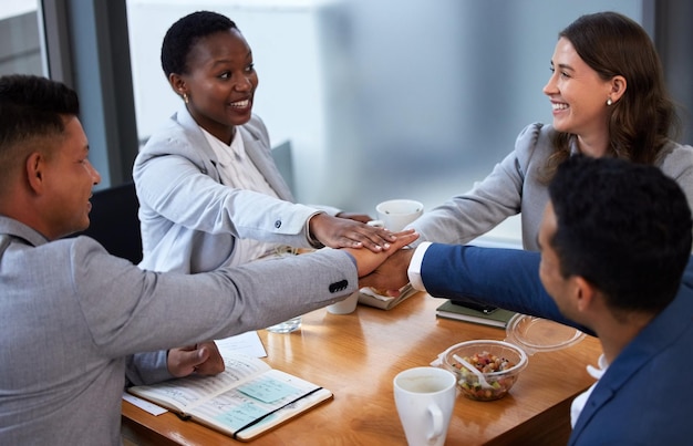 私たちの誰もが私たち全員ほど賢い人はいない現代のオフィスで会議と朝食をしている同僚のグループのショット