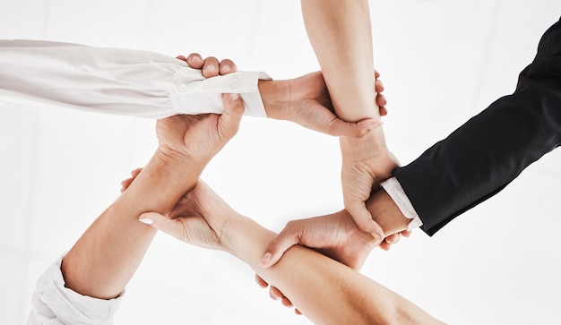 None of us is as strong as all of us Low angle shot of a group of businesspeople holding one anothers wrists in a circular formation