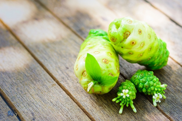 Photo noni fruit and blossom on old wooden table.