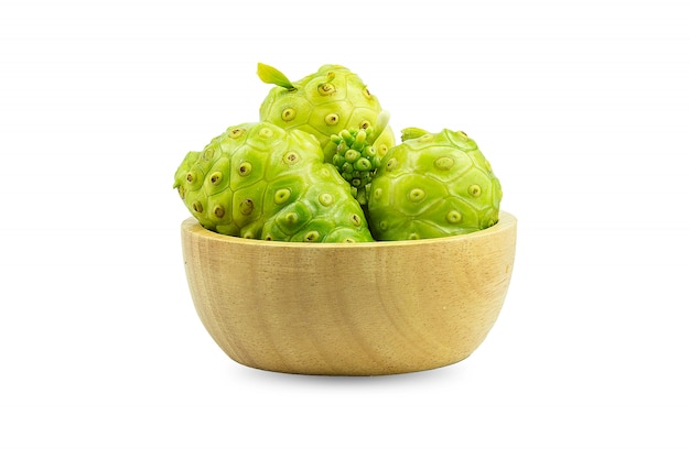 Noni o morinda citrifolia e pezzi in una tazza di legno, separati su uno sfondo bianco.