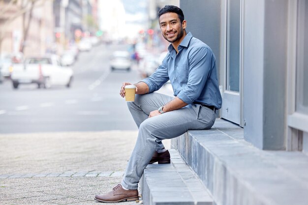 Nood aan een koffiestoot Shot van een jonge zakenman die een kopje koffie drinkt in de stad