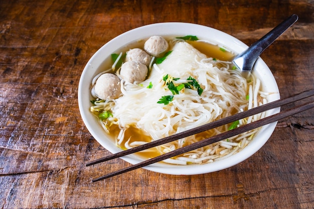 Noodle and meatballs in a bowl on a wooden table