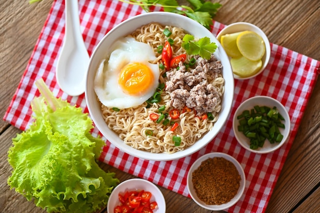 Noodles bowl with boiled egg minced pork vegetable spring onion lemon lime lettuce celery and chili on table food instant noodles cooking tasty eating with bowl noodle soup