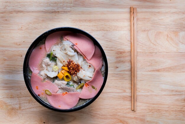 Noodles in a bowl with ham and pork served