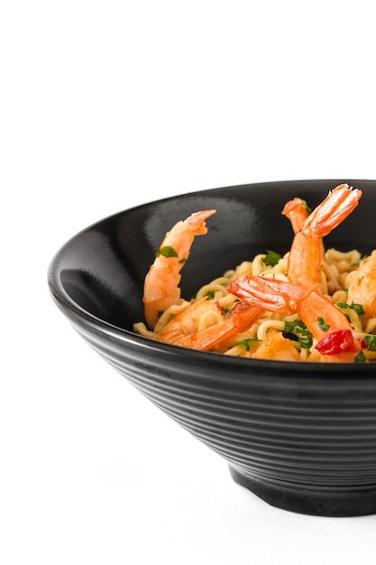 Noodles and shrimps with vegetables in black bowl isolated on white