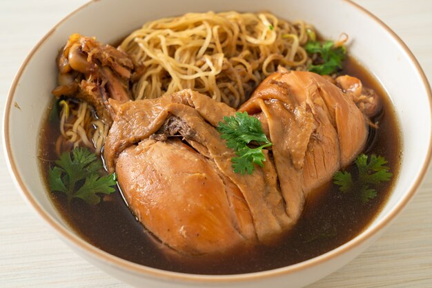 Tagliatelle con pollo brasato in una ciotola di zuppa marrone - stile di cibo asiatico