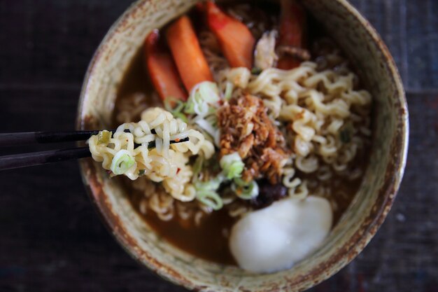 木の背景に卵のスパイシーなスープと麺