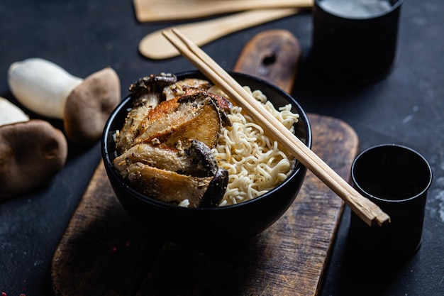 Noodles with eringi mushrooms in a black plate