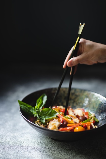 暗い背景に魚介類と野菜を入れた麺。アジア料理。