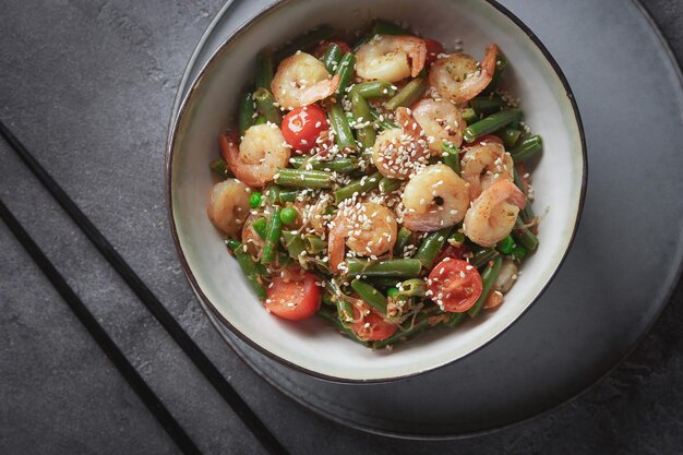 Noodles with shrimps and vegetables, Asian cuisine, Glass chinese noodles, Gray background, Selective focus