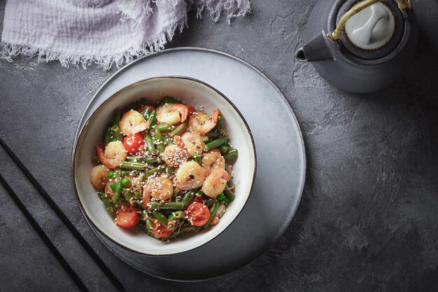 Лапша с креветками и овощами, азиатская кухня, стеклянная китайская лапша, серый фон, выборочный фокус