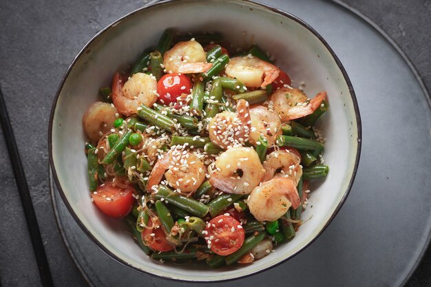 Noodles with shrimps and vegetables, Asian cuisine, Glass chinese noodles, Gray background, Selective focus