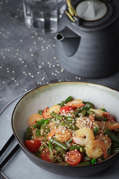 Noodles with shrimps and vegetables, Asian cuisine, Glass chinese noodles, Gray background, Selective focus