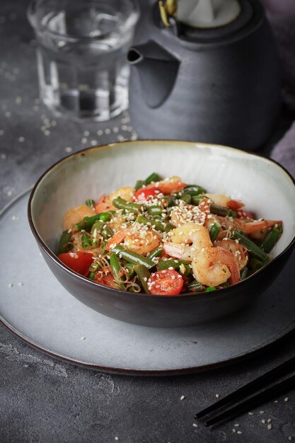 Noodles with shrimps and vegetables, Asian cuisine, Glass chinese noodles, Gray background, Selective focus