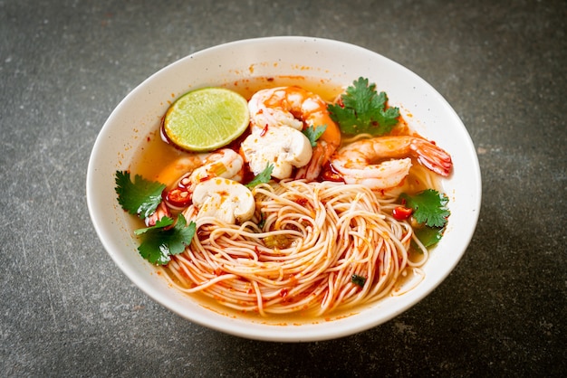 noodles with spicy soup and shrimps in white bowl (Tom Yum Kung) 