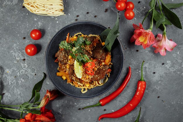 Noodles with veal and vegetables on a gray table