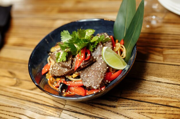 Noodles with veal and vegetables on a gray table