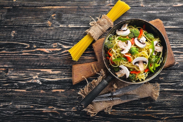 フライパンに野菜が入った麺アジア料理パスタ上面図フリースペース木製の背景に