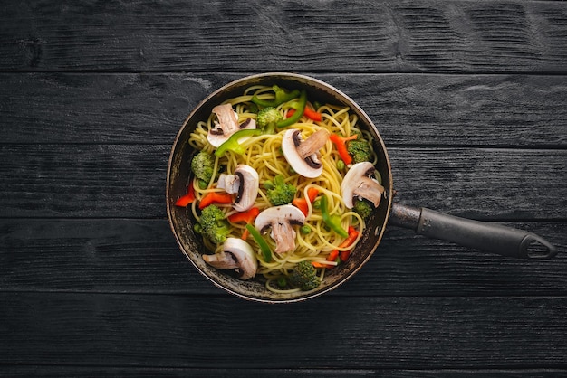 Noodles with vegetables in a frying pan Asian Cuisine Pasta Top view Free space On a wooden background