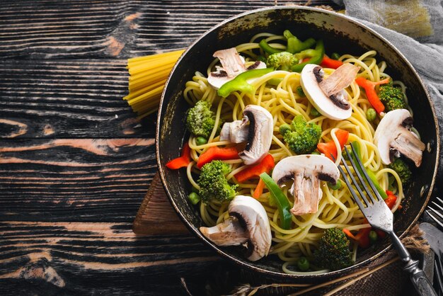 Noodles with vegetables in a frying pan Asian Cuisine Pasta Top view Free space On a wooden background