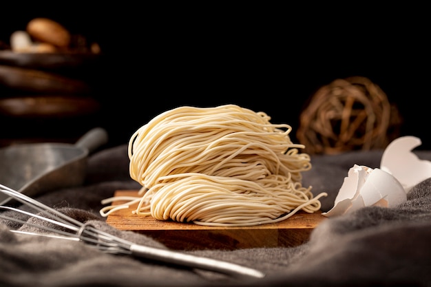 Foto tagliatelle su un piatto di legno su uno sfondo nero