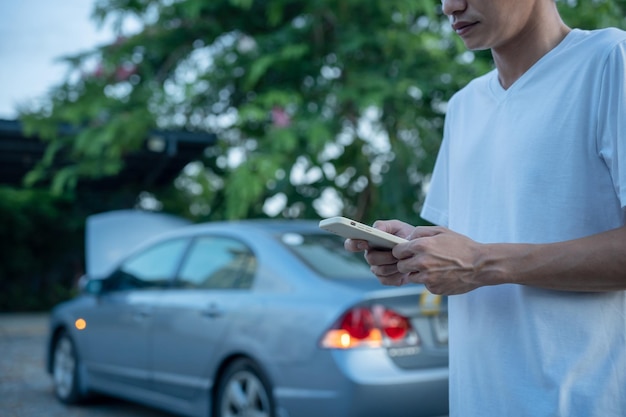 Noodveiligheidsman belt een mobiele telefoon voor een noodnummer vanwege een autopech in het bos onderhoud van de auto voor de reis verhoogt de veiligheid bij ongevallen