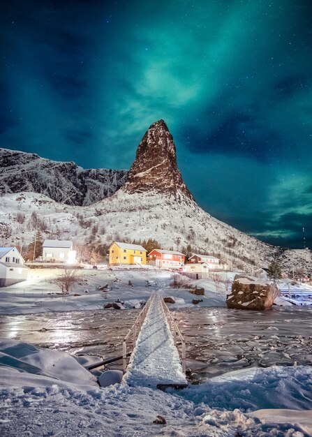 Noordelijke lichten over berg met kleuren Skandinavisch dorp in Lofoten