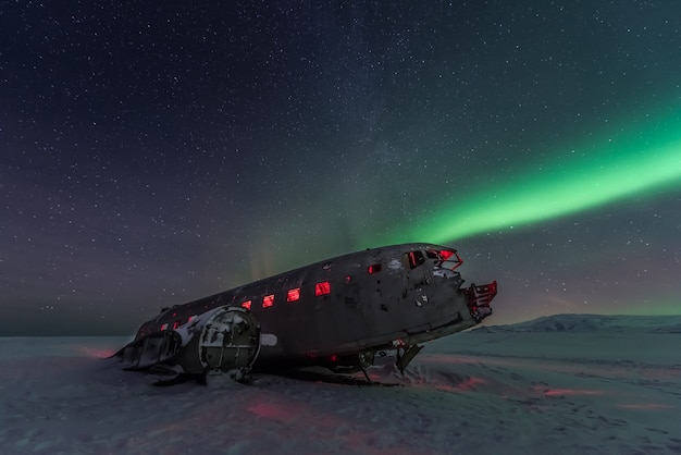 Noordelijke lichtenaurora borealis over vliegtuigschipbreuk in IJsland