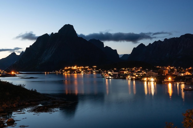 Noorwegen reine vissersdorp in het blauwe uur met berg- en dorpsreflectie in het water