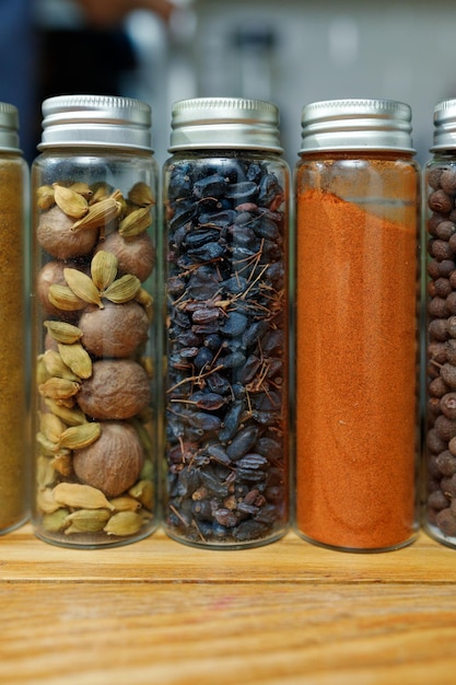 Nootmuskaat kardemom gedroogde berberis en paprika in transparante potten onder andere kruiden op tafel in de thuiskeuken