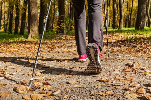 Nordic walking adventure and exercising concept woman hiking legs and nordic walking poles in autumn nature