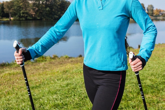 Nordic walking exercise adventure hiking concept closeup of woman's torso and hands holding nordic walking poles