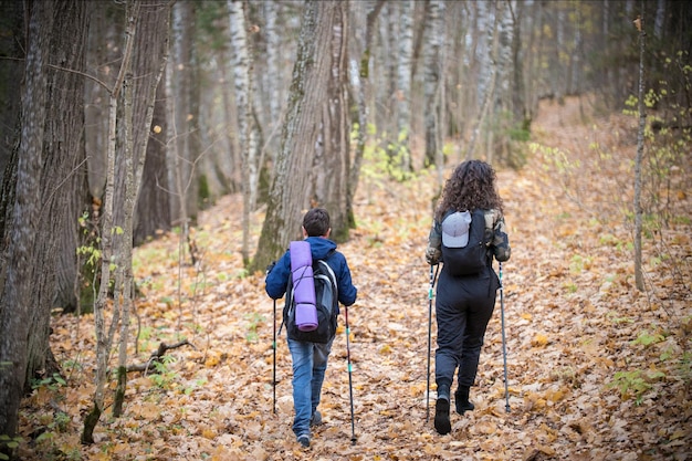 Nordic walking jongetje en jonge vrouw achteraanzicht herfstseizoen