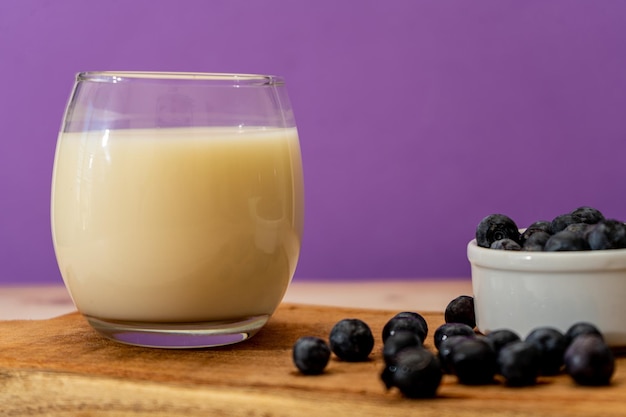 Normaal beeld van een glas melk naast wat bosbessen in een moderne uitgeklede setting Gezond eten