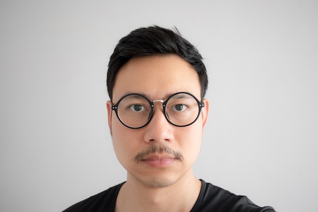 Normal face of Asian nerd guy with eyeglasses and mustache.