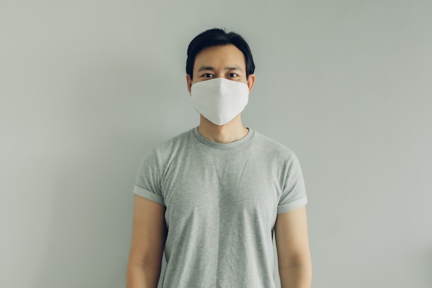 Normal face of man wearing white hygienic mask in grey t-thirt with copy space.