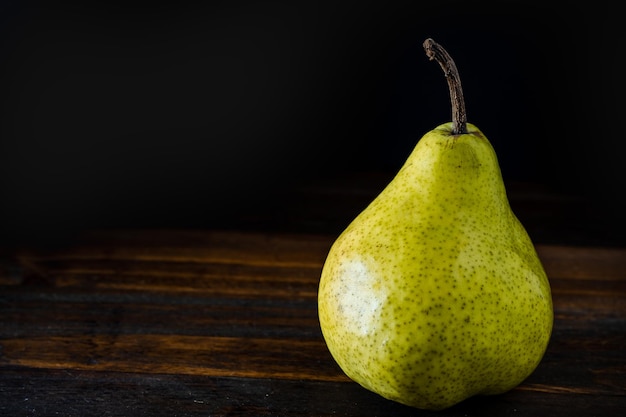 Normal view of a green or packham pear on a table Dark background Organic and natural products healthy and wholesome food