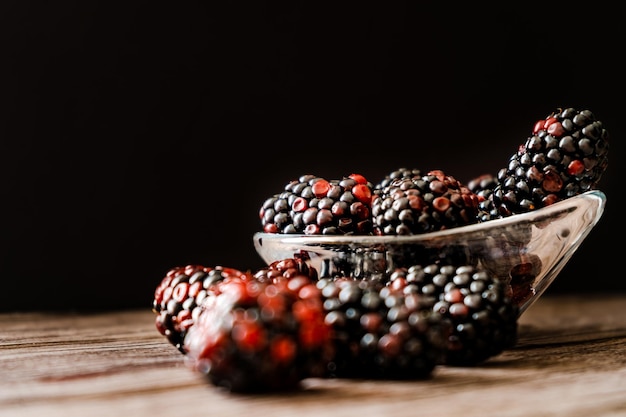 Normal view of a Serving of Blackberries in a small clear bowl on a rustic wood table Horizontal orientation space for text Dark food